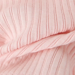 Gros plan détaillé sur le tissu en maille côtelée rose montrant la texture douce et les motifs