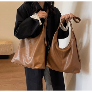 Close-up of a large brown soft leather tote bag shown on a model for size and drape