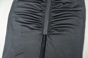 Detail of black slim fit dress featuring ruched design and elegant side slit texture