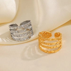 Stacked gold and silver hammered stainless steel open rings on beige silk fabric background