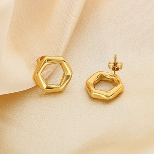 Modern 18K gold-plated hexagonal hollow stud earrings on champagne silk fabric