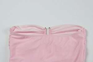 Detail von hellrosa trägerlosem Kleid mit plissiertem Stoff und Goldperlen