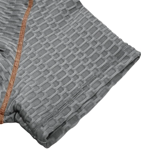 Gros plan du tissu jacquard nid d'abeille gris avec des coutures décoratives brunes