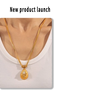 Detail of gold teardrop pendant with star pattern and pearl on black beaded chain