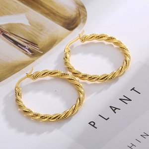 Detailed macro view of golden twisted hoop earrings on a fashion magazine background