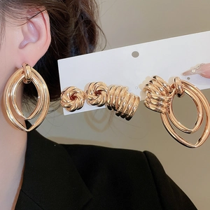 Macro view of gold geometric metal earring set with twisted knot studs and ear cuffs