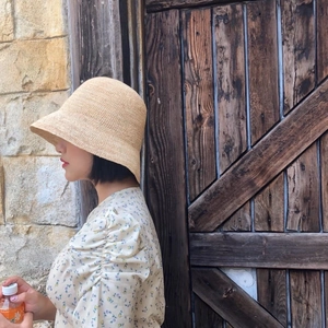 Side view of a handmade raffia bucket hat for women on a model in an outdoor summer setting