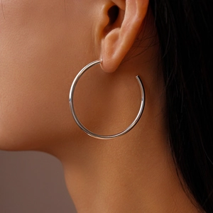 Close-up of a silver polished large C-shaped hoop earring worn by a female model
