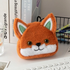 Close-up of a cute orange fox plush coin purse with embroidery details on a white desk