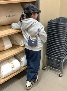 Détail du mini sac lune en denim bleu avec poignée marron et bandoulière chaîne