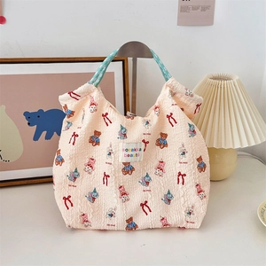 Detail of cream canvas tote bag with cartoon animal prints and blue braided handles