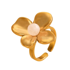 Close-up of golden four-petal flower ring with pink bead and matte metallic finish