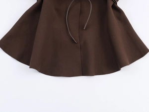 Dettaglio dell'orlo della gonna in maglia marrone scuro con cintura da annodare