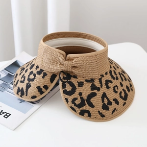 Detail of straw sun visor featuring leopard print brim and woven bow decoration
