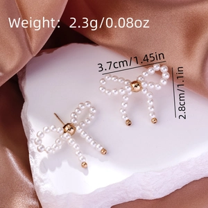 Detailed view of pearl bow earrings with size measurements on champagne satin