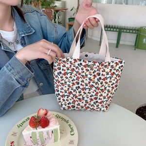 Close-up of corduroy handbag with red floral print and snap button closure