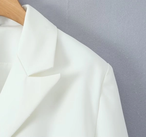 Detail of white blazer collar and shoulder stitching on wooden hanger