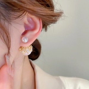 Close-up of double-sided pearl earrings with gold crown setting and crystal inlay