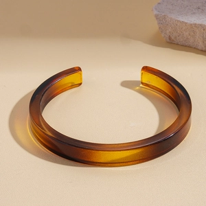 Detailed view of an amber acrylic open cuff bracelet with geometric resin texture