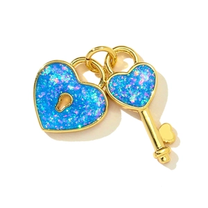 Detail of gold heart lock and key pendants with blue opal texture and iridescent shimmer