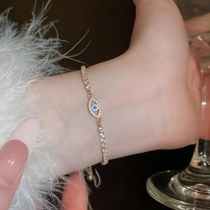 Macro view of gold-plated evil eye bracelet with sparkling zircons on a female wrist