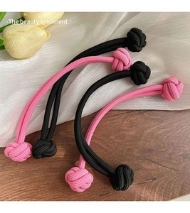 Détail d'élastiques à cheveux tressés roses et noirs avec design à double nœud