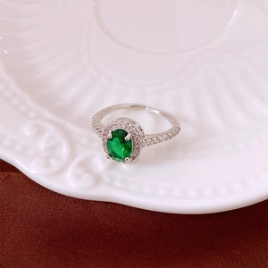 Macro detail of silver adjustable ring with green oval zircon on white ceramic plate