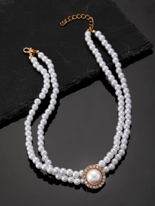 Detailed view of luxury double-layer pearl necklace with sparkling gold pendant on black surface