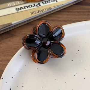 Close-up of amber and black flower hair claw clip on a decorative tray for styling