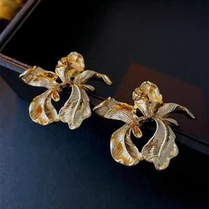 Macro detail of golden flower earrings showing intricate textured metal petals on black box