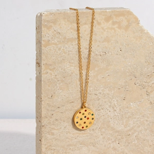 Detailed shot of a gold round pendant necklace with multicolor zircon on beige stone