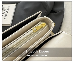 Detail view of the smooth golden zipper and internal compartments on the cream leather bag