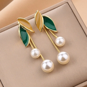 Detailed macro view of forest-style leaf earrings with enamel finish and pearl tassels
