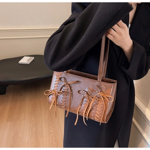 Close-up of brown leather hobo bag featuring woven texture and bow lace-up details