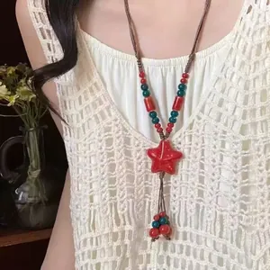 Détail du collier étoile en céramique rouge avec perles colorées et cordon ciré