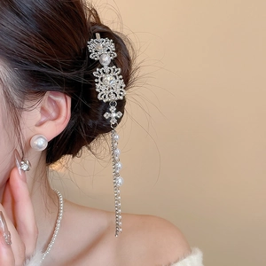 Macro detail of silver tassel hair clip with rhinestones and hanging pearls on a model