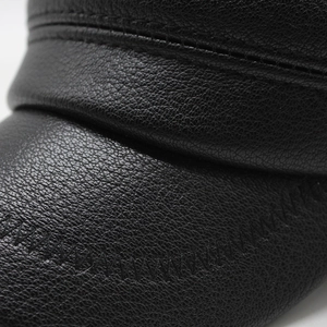 Macro shot of black faux leather flat cap showing lychee texture and fine double stitching