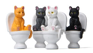 Close-up of four funny miniature cats sitting on white toilets for creative garden decor