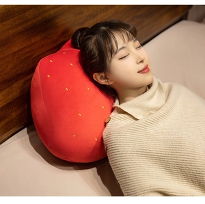 Soft plush strawberry cushion with yellow polka dots used as a comfortable headrest