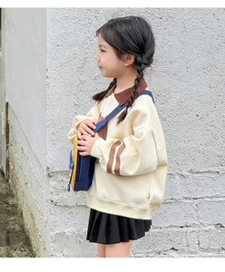 Detail of cartoon car crossbody bag styled with a kid's preppy sweatshirt and skirt
