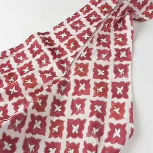 Vue macro détaillée du tissu blanc présentant des motifs floraux rouges et papillons