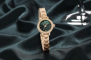 Detail of rose gold watch with green malachite dial and rhinestone bezel on silk