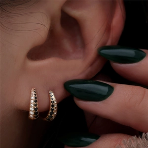Close-up of gold huggie earrings with double rows of black and white crystals on ear