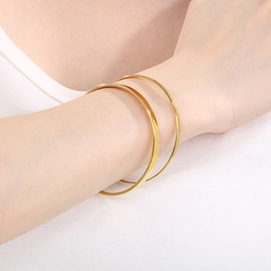 Close-up of dual stacked minimalist gold titanium steel bangles on model's wrist