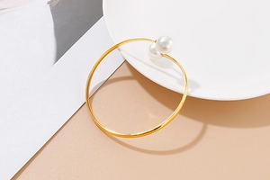 Detail of minimalist gold open cuff bracelet featuring two lustrous white pearls on ceramic