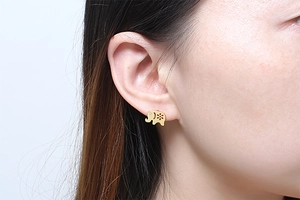 Detail of golden elephant stud earring with floral engraving and zircon on ear