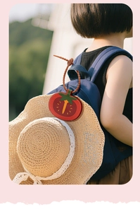 Close-up of a red tomato-shaped leather magnetic hat clip attached to a blue backpack