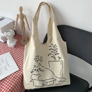 Detailed view of cream canvas tote bag with black cat illustration on a black chair