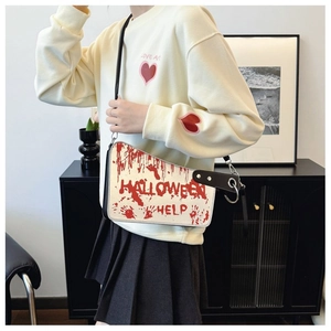Detail of cleaver-shaped crossbody bag with red blood splatter and Halloween Help text