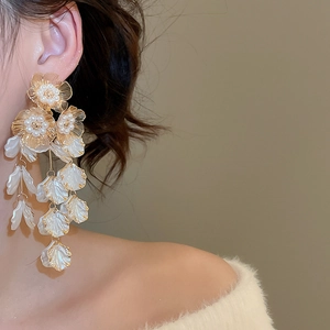 Detailed side view of long tassel earrings with pearl flower design on a model